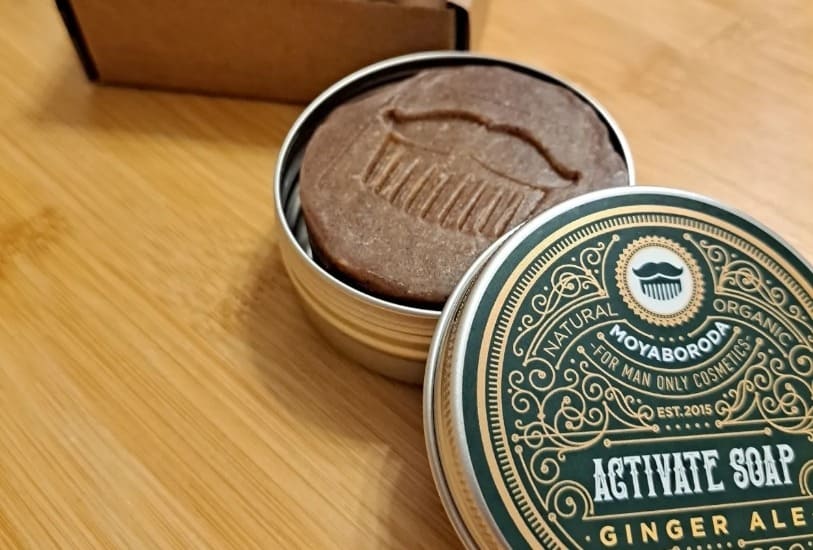 A finished round bar of handmade natural soap in a metal tin